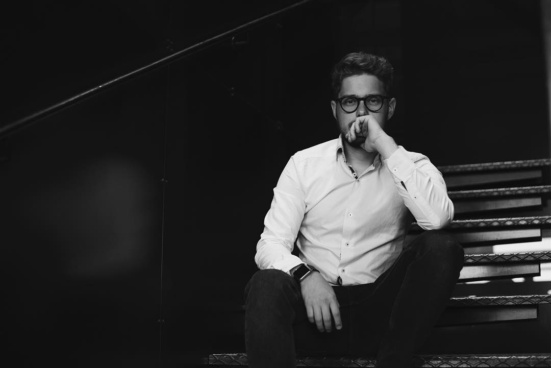 Dmitry Kochergin seated on a staircase in a black-and-white portrait.